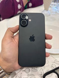 someone holding an iphone in their hand with the back camera facing up on a table