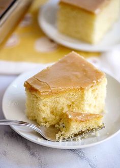 a piece of cake on a white plate with a fork next to it and another slice in the background