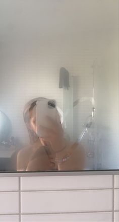 a woman taking a selfie in front of a mirror with her reflection on the wall