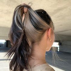 a woman with her hair in a pony tail braid, looking at an object hanging from the ceiling