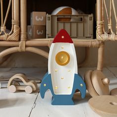 a wooden toy rocket ship sitting on top of a floor next to toys and other items