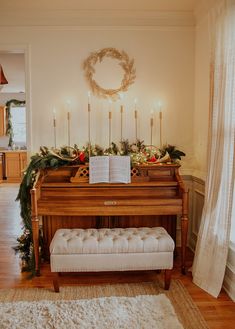 an open book sitting on top of a piano in front of a christmas wreath and candles