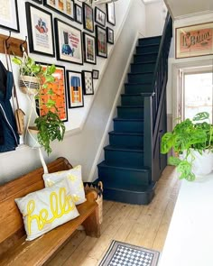 a staircase with pictures on the wall and a wooden bench in front of it next to a potted plant