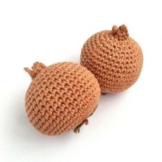 two crocheted pomegranates sitting next to each other on a white surface