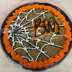 an orange and white decorated cake with the word boo on it's side in front of a spider web