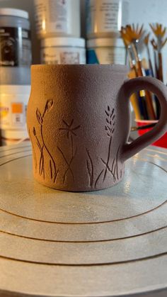 a coffee cup sitting on top of a counter next to paintbrushes and other art supplies