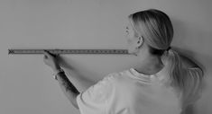 a woman is measuring the wall with a tape measure ruler in her hand and looking up