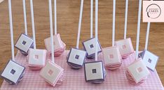 there are many square and square objects on the pink tablecloth with white sticks sticking out of them