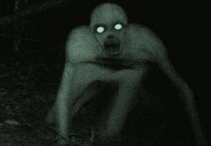 a man with glowing eyes crouching down in the dark