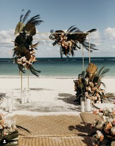 an outdoor ceremony set up on the beach with palm trees and flowers in vases