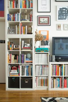 a bookshelf filled with lots of books next to a tv on top of a hard wood floor