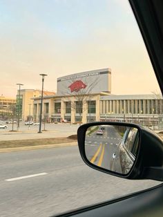 a car is driving down the road in front of a building with a red bull on it's side