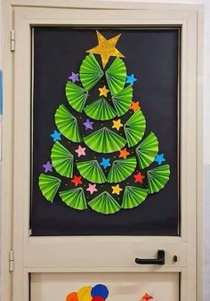 a christmas tree made out of green paper on a white door with decorations around it