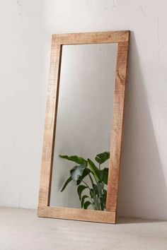 a mirror sitting on top of a white counter next to a potted green plant