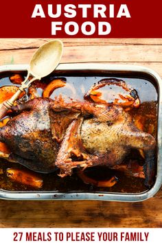 a roasting pan filled with meat and vegetables on top of a wooden table next to a