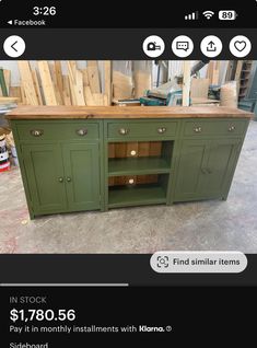 a green kitchen island with drawers and cupboards on the top, next to a pile of wood planks