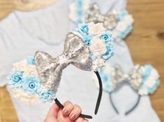 a person holding up a headband with flowers and bows on it in front of a wooden table