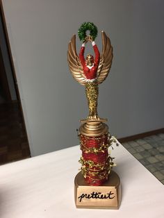 a gold and red christmas decoration on top of a white table with a sign that says puttin out