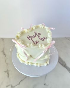 a wedding cake with the word bride to be written on it and pink ribbon around the edge