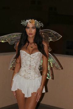 a woman in a white corset and fairy wings is posing for the camera