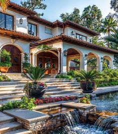 a large house with steps leading up to it and a waterfall in the front yard