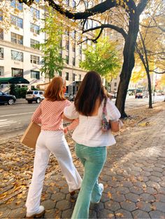 two women walking down the street with their hands in each other's back pockets