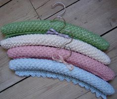 five crocheted headbands are hanging from hooks on a wooden floor,