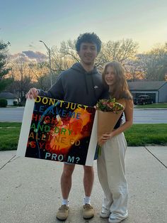 two people standing next to each other holding a sign