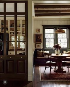 a dining room table and chairs in front of a large window with wooden beams on the ceiling