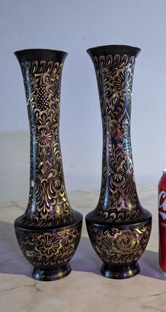 two vases sitting next to each other on a table with a soda can in the background