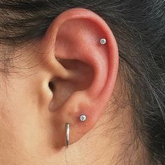 a close up of a person's ear with three piercings