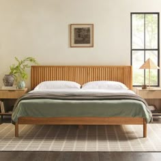 a bed sitting in a bedroom next to a wooden dresser and table with two lamps on it