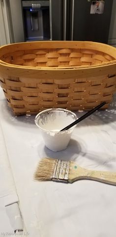 a wooden basket sitting on top of a table next to a paintbrush and brush