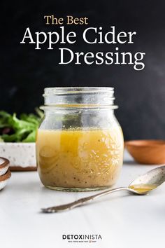 the best apple cider dressing in a glass jar with spoons next to it