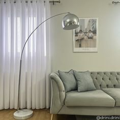 a living room with a couch, lamp and pictures hanging on the wall above it