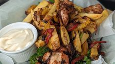 a basket filled with fries and ketchup next to a bowl of mayonnaise