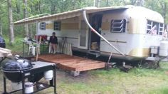 an rv is parked in the woods next to a picnic table and bbq grill