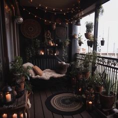 a balcony with potted plants and candles on the floor, lit by string lights