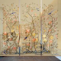 two glass panels with flowers and birds on them in front of a white wall,