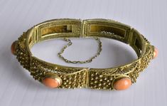 This is a very fine vintage Chinese gold gilt silver filigree hinged bracelet with 6 high quality and high density genuine and natural bezel-set oval salmon red coral cabs. Marked "SILVER". In great vintage condition. It measures 7-1/4" long by 1/2" wide and weighs 29.8 grams. Each of the 6 coral cabs measures 10 mm x 8 mm each.  From the 1940's. Formal Coral Jewelry With Cabochon Details, Formal Coral Jewelry With Cabochon, Handmade Oval Bangle For Formal Events, Elegant Oval Coral Jewelry, Handmade Oval Bangle For Formal Occasions, Elegant Coral Oval Jewelry, Vintage Oval Coral Jewelry, Vintage Coral Oval Jewelry, Coral Oval Jewelry For Weddings