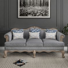 a gray couch with blue and white pillows in a room next to a painting on the wall