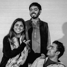 two men and a woman sitting next to each other in front of a white wall