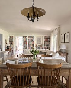 two wooden chairs sitting at a table in front of a book shelf filled with books