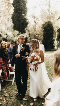 a bride and her father walking down the aisle at their outdoor wedding ceremony in autumn