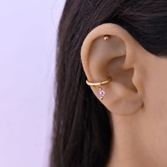 a woman's ear is shown with a single pink stone in the middle of it