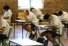 several students are sitting at desks writing