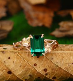 an emerald colored ring sitting on top of a leaf