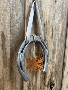 a pair of scissors hanging on a wooden door with a fall leaf attached to it