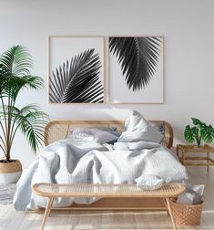 a bed with white sheets and pillows next to two palm leaves on the wall above it