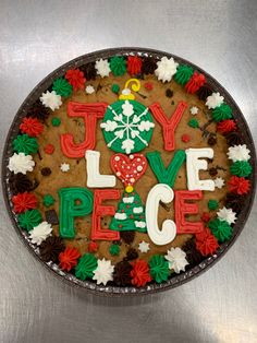 a cookie decorated with the words joy, love, peace and christmas tree on it